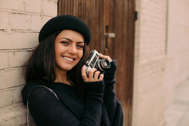 Mujer sosteniendo cámara retro y tomando fotos