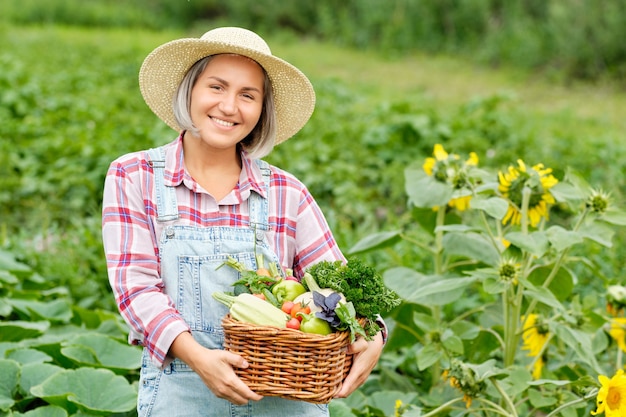 Mujer sosteniendo una canasta llena de cosecha de hortalizas orgánicas y raíz en Organic Bio Farm. Cosecha de hortalizas de otoño.