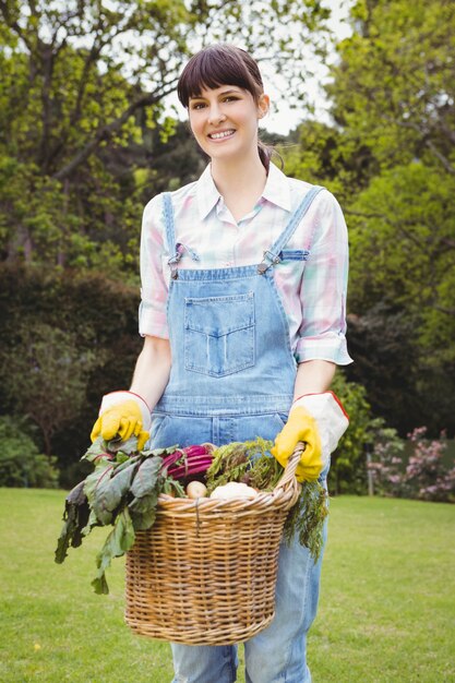 Mujer sosteniendo una canasta de verduras recién cosechadas en el jardín