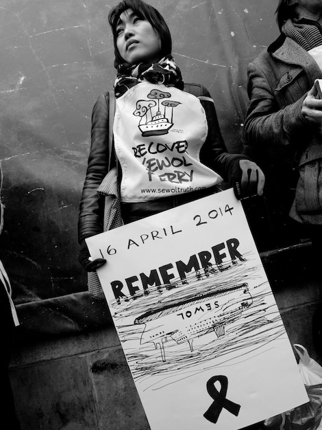 Mujer sosteniendo un cartel mientras está de pie contra la pared