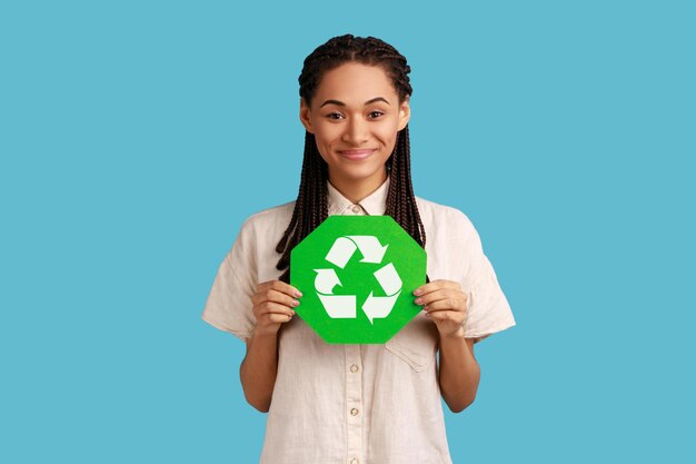 Foto mujer sosteniendo un cartel de reciclaje verde en la mano y mirando seriamente a la cámara pensando en verde