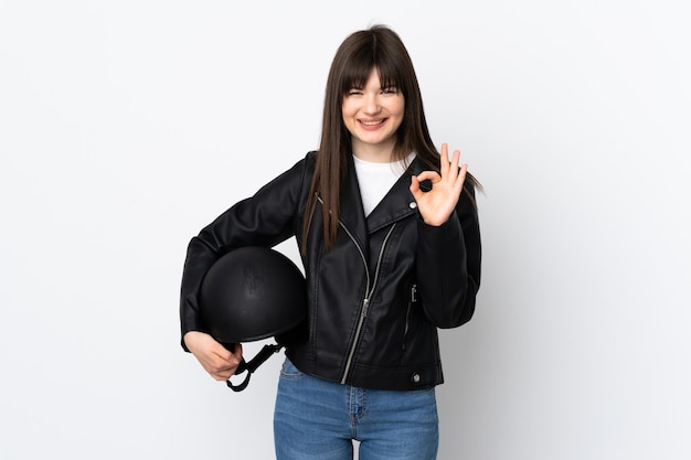 Mujer sosteniendo un casco de motocicleta aislado en blanco mostrando un signo de ok con los dedos