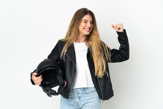 Mujer sosteniendo un casco de motocicleta aislado en la pared blanca haciendo un gesto fuerte