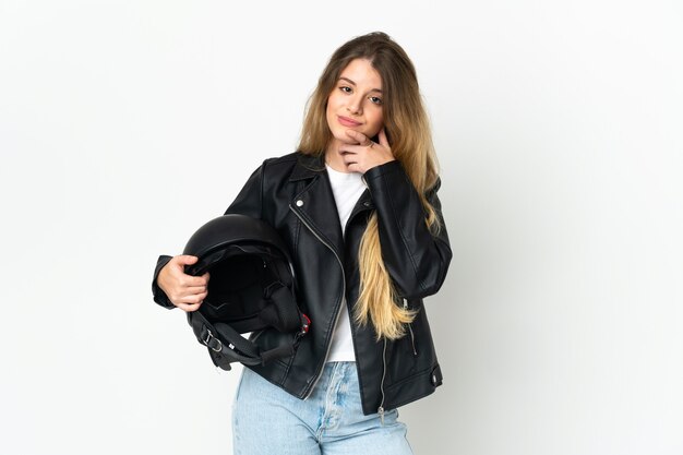 Foto mujer sosteniendo un casco de motocicleta aislado en el pensamiento de pared blanca