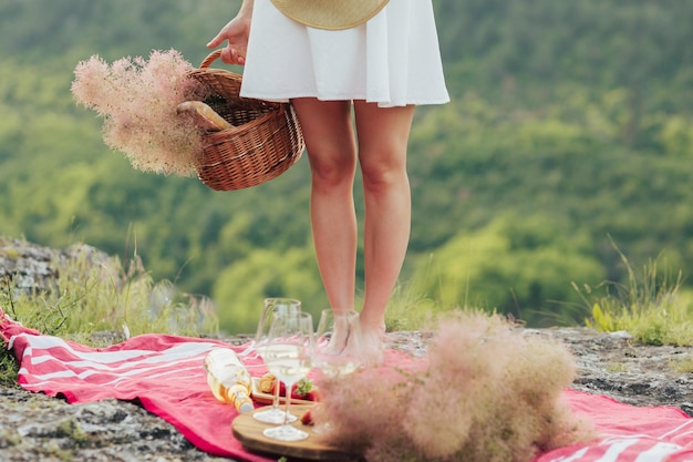 Mujer sosteniendo cesta de picnic con flores y baguette