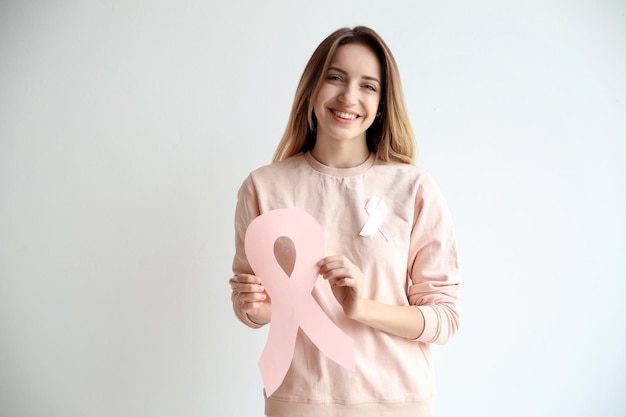 Mujer sosteniendo cinta de papel rosa sobre fondo blanco Concepto de concientización sobre el cáncer de mama