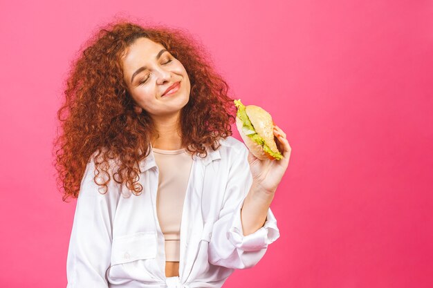 Mujer sosteniendo y comiendo una hamburguesa grande