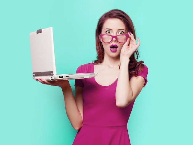 Una mujer sosteniendo una computadora portátil con un sombrero rosa en la cabeza.