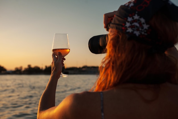 Una mujer sosteniendo una copa de vino frente a un lago.