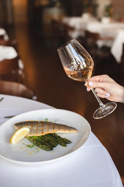 Una mujer sosteniendo una copa de vino y un plato de espárragos.