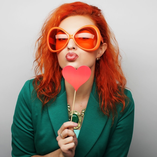 Mujer sosteniendo un corazón de fiesta y gafas.