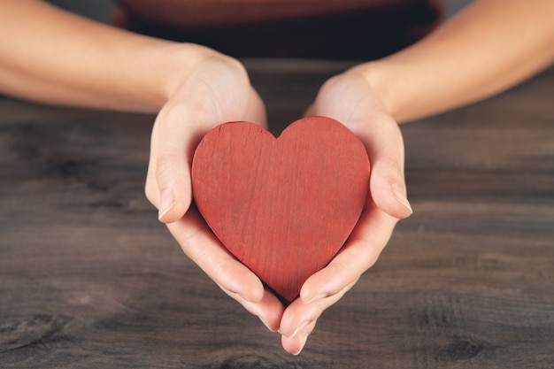 Mujer sosteniendo un corazón de madera en sus manos