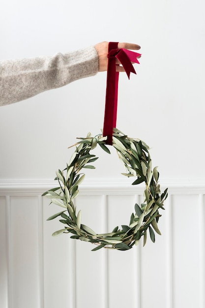 Mujer sosteniendo una corona de Navidad fresca