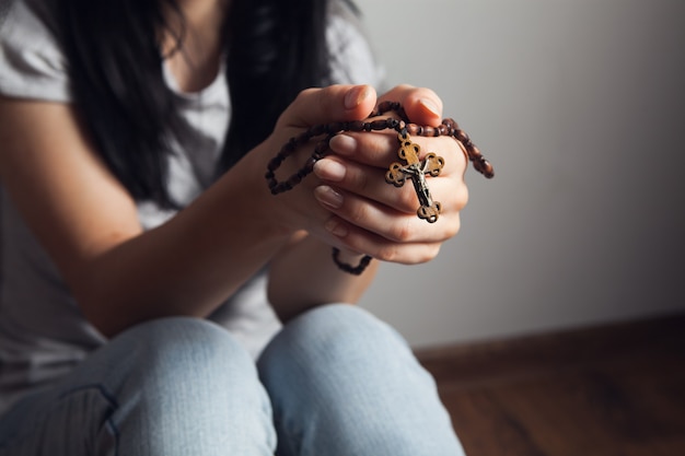 Mujer sosteniendo una cruz y rezando en el suelo