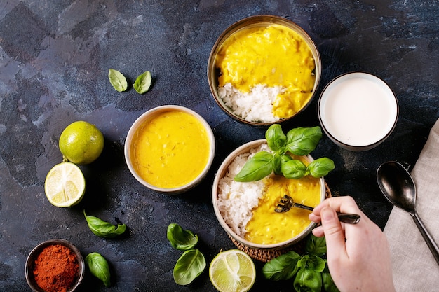 Mujer sosteniendo cuenco de cerámica de curry amarillo servido con albahaca y limas