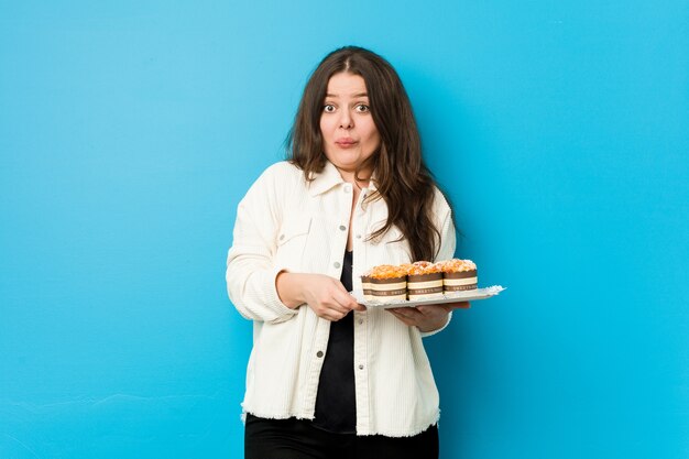 Mujer sosteniendo cupcakes en estudio