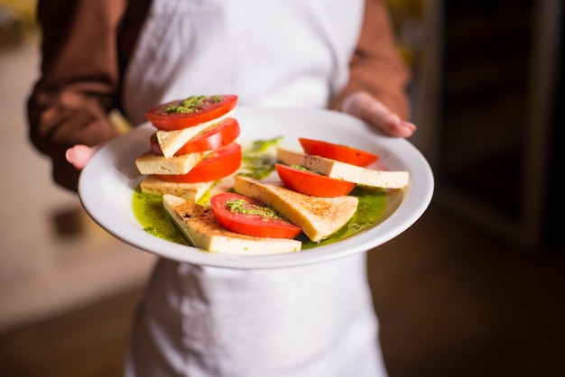 Mujer sosteniendo deliciosas comidas vegetarianas ensalada de tomate Caprese