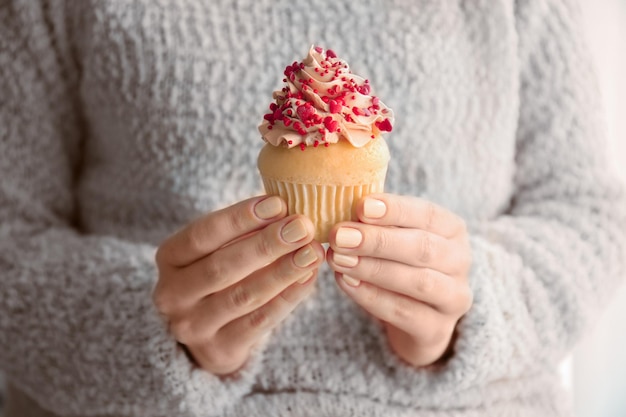 Mujer sosteniendo delicioso cupcake para el Día de San Valentín