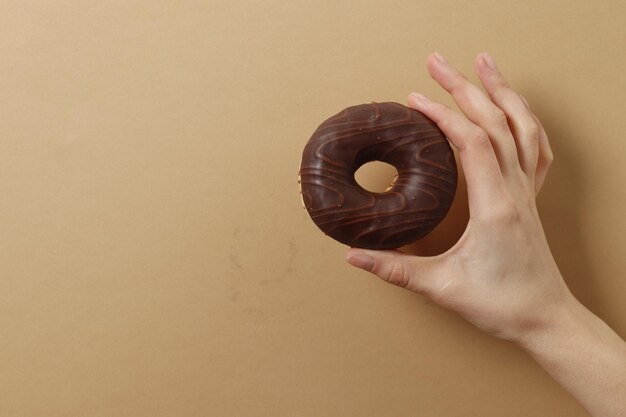 Mujer sosteniendo delicioso donut sobre fondo de color