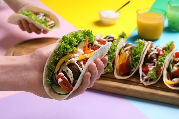 Mujer sosteniendo delicioso taco contra primer plano de fondo de color