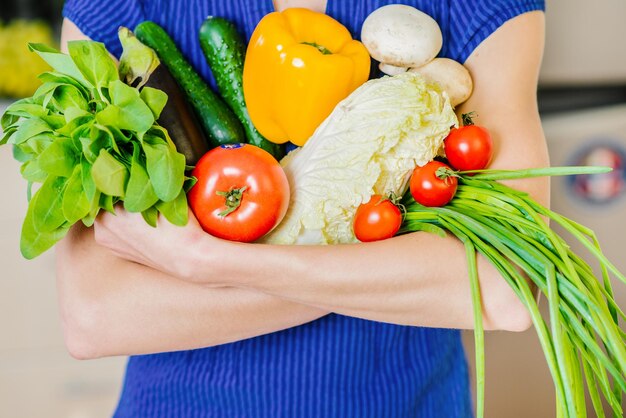 Mujer sosteniendo diferentes verduras, primer plano. Comida sana