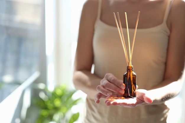 Mujer sosteniendo difusor con palos de madera para aceite aromático