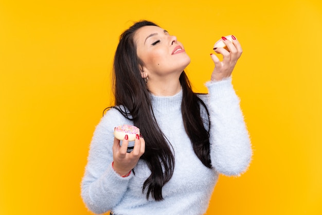 Mujer sosteniendo donas sobre pared aislada