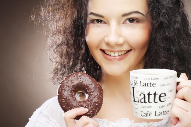 Mujer sosteniendo donut y café en la mano