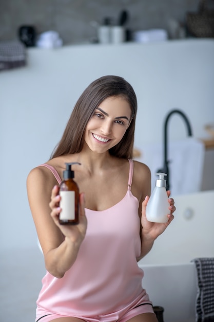 Mujer sosteniendo dos botellas de productos para el cuidado de la piel