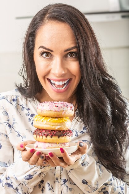 Mujer sosteniendo con entusiasmo el plato lleno de donas.