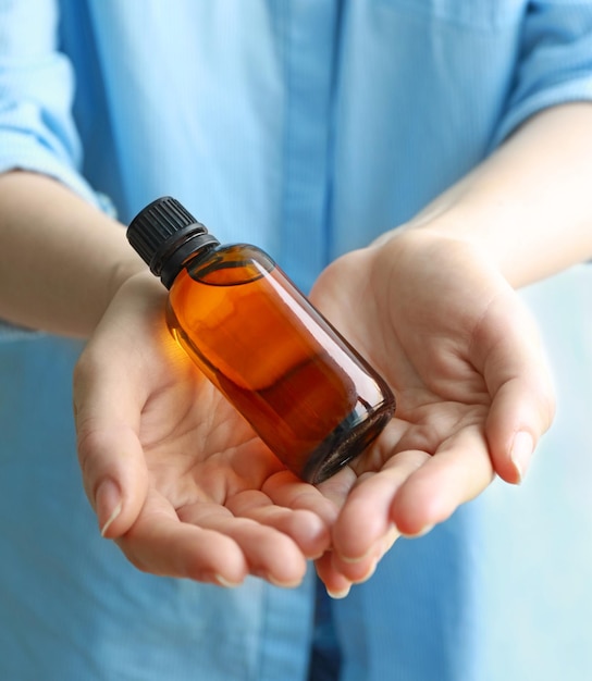 Mujer sosteniendo extracto de vainilla aromático en botella de cerca