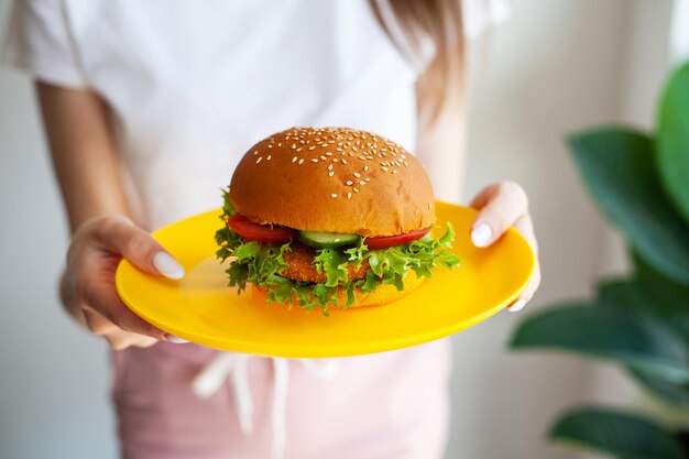 Mujer sosteniendo fatburger dañina en placa amarilla