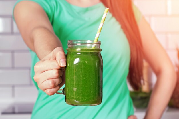 Mujer sosteniendo un frasco de vidrio con batido verde saludable