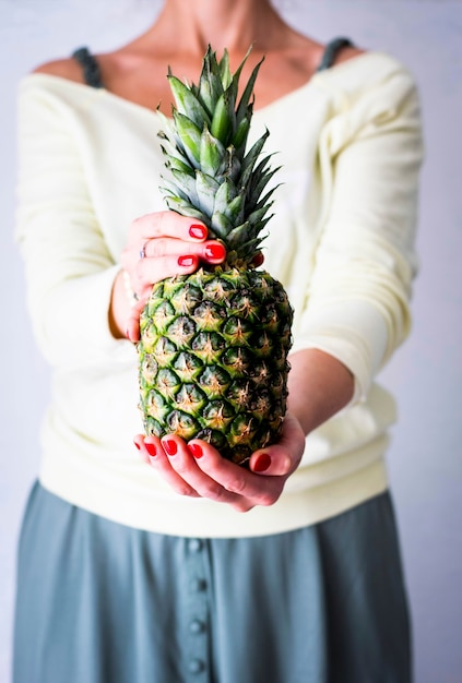 Mujer sosteniendo frutas tropicales de piña orgánica