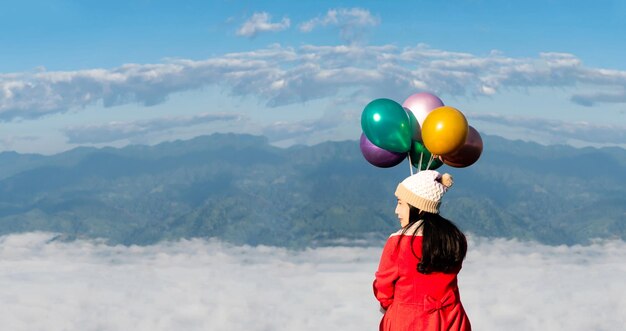 Mujer sosteniendo globos de colores viajan montañas y niebla