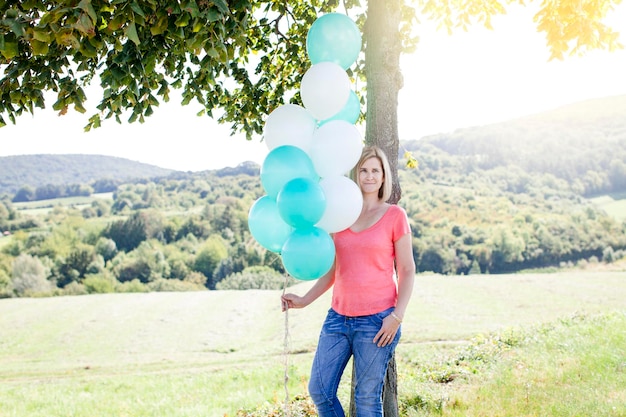 Foto mujer sosteniendo globos de helio mientras está de pie en el campo