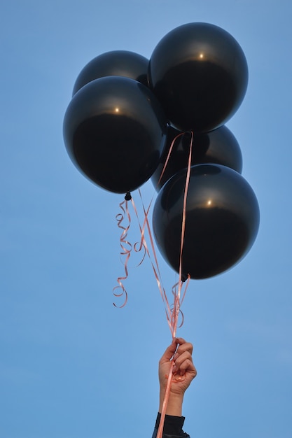 Mujer sosteniendo globos negros