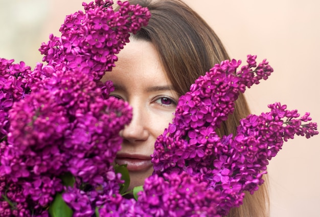 Foto mujer sosteniendo un gran ramo de flores lilas de cerca