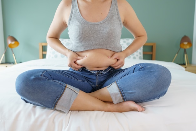 Mujer sosteniendo grasa abdominal excesiva