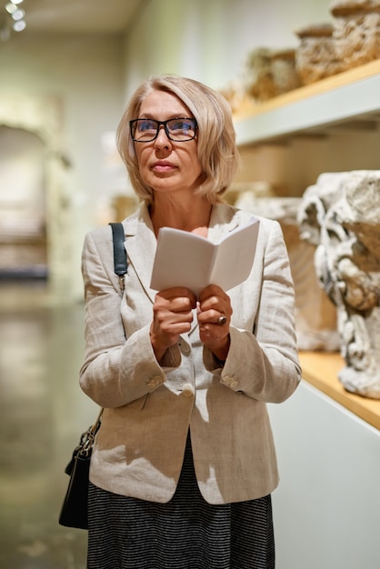 Mujer sosteniendo una guía dentro de un museo