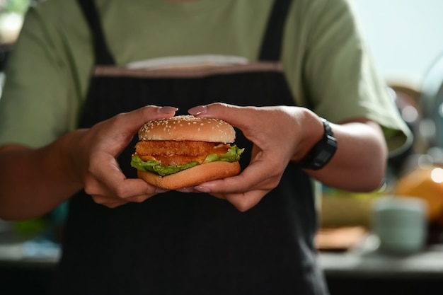 Mujer sosteniendo hamburguesas caseras en las manos.