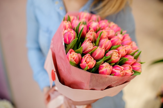 Mujer sosteniendo un hermoso y tierno ramo de tulipanes rosados