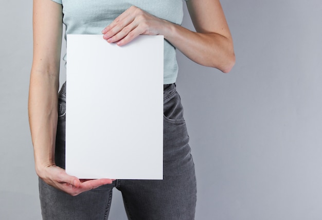 Foto mujer sosteniendo una hoja de papel vacía en blanco