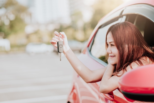 Mujer sosteniendo la llave del coche en su coche nuevo