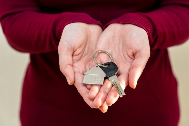 Mujer sosteniendo llave con llavero en forma de casa