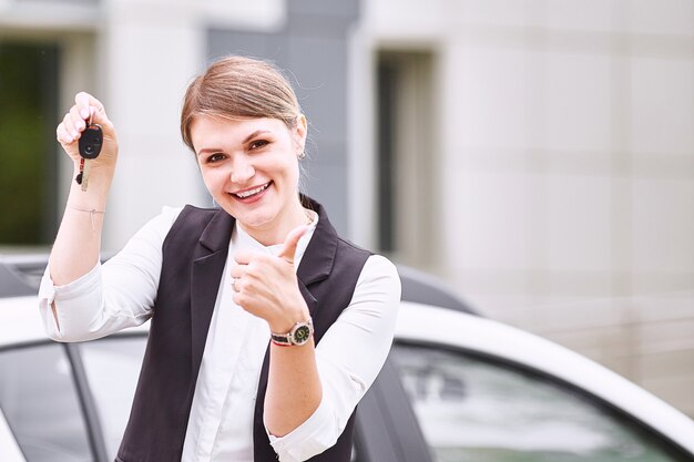 Mujer sosteniendo las llaves del auto nuevo y sonriendo a la cámara