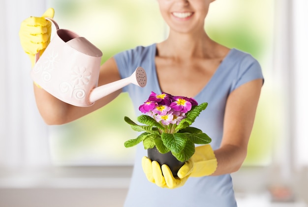 mujer sosteniendo maceta con flor y regadera