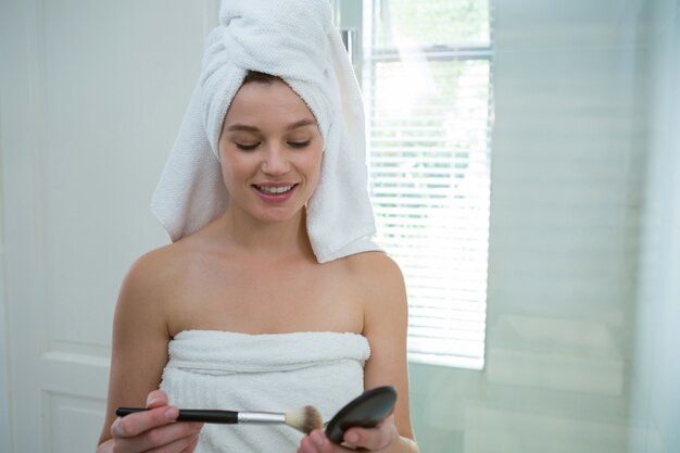 Mujer sosteniendo maquillaje en baño