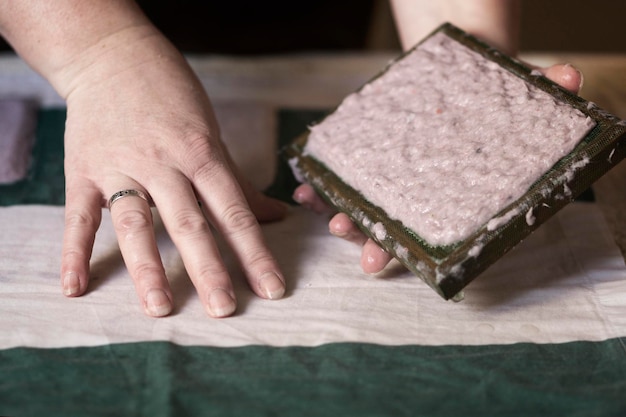 Una mujer sosteniendo un marco para hacer hojas de papel a partir de papel reciclado. Enfoque selectivo. Hobby del hogar, reciclaje de papel. El concepto de cero residuos, reciclaje, ecología.