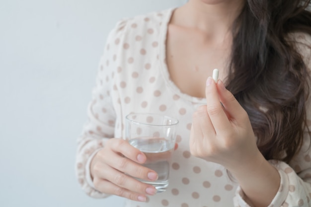 Foto una mujer sosteniendo una medicina y un vaso de agua en la mano. conceptos médicos y de salud.